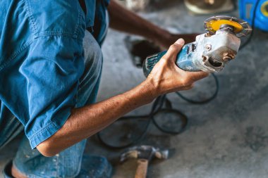 Su tesisatı bakım servisi evdeki kanalizasyon kanallarını değiştirmek için açılı öğütücü kullanıyor. Yaşlı adam kanalizasyon sisteminin lağım kapağını değiştirip onarıyor. Tuvalet drenaj sisteminin bakımı