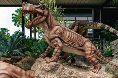 PATTAYA, THAILAND-DECEMBER 30. 2018: Nong Nooch Tropikal Botanik Bahçesi 'ndeki canlı benzeri manzaraya karşı heykeli veya çeşitli gerçekçi dinozor heykeli olan dinozor vadisi.