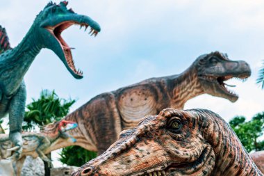 PATTAYA, THAILAND-DECEMBER 30. 2018: Nong Nooch Tropikal Botanik Bahçesi 'ndeki canlı benzeri manzaraya karşı heykeli veya çeşitli gerçekçi dinozor heykeli olan dinozor vadisi.