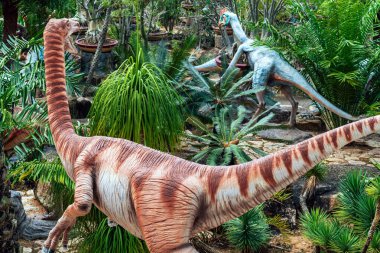 PATTAYA, THAILAND-DECEMBER 30. 2018: Nong Nooch Tropikal Botanik Bahçesi 'ndeki canlı benzeri manzaraya karşı heykeli veya çeşitli gerçekçi dinozor heykeli olan dinozor vadisi.
