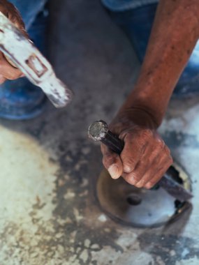 Su hizmetleri bakım servisinin yaşlı çalışanı evdeki kanalizasyon kanallarını değiştiriyor. Yaşlı adamın elleri kanalizasyon sisteminin lağım kapağını değiştirip onarıyor. Tuvalet drenaj sisteminin bakımı.