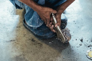 Su tesisatı bakım servisi evdeki kanalizasyon kanallarını değiştirmek için açılı öğütücü kullanıyor. Yaşlı adam kanalizasyon sisteminin lağım kapağını değiştirip onarıyor. Tuvalet drenaj sisteminin bakımı