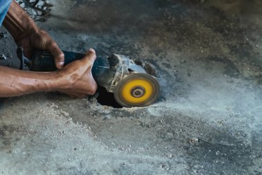 Su tesisatı bakım servisi evdeki kanalizasyon kanallarını değiştirmek için açılı öğütücü kullanıyor. Yaşlı adam kanalizasyon sisteminin lağım kapağını değiştirip onarıyor. Tuvalet drenaj sisteminin bakımı