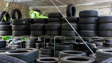 Eski model, araba tamirhanesinde üst üste yığılmış pek çok tekerlek kullanırdı. Eski siyah lastik lastik yığınları. Arka planda pnömatik lastik yığını var. Geri dönüşüm için eski lastik deposu. Araç parçası. Tekerlek lastikleri