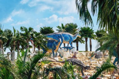 PATTAYA, THAILAND-DECEMBER 30. 2018: Nong Nooch Tropikal Botanik Bahçesi 'ndeki canlı benzeri manzaraya karşı heykeli veya çeşitli gerçekçi dinozor heykeli olan dinozor vadisi.
