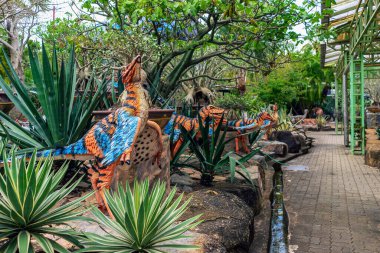 PATTAYA, THAILAND-DECEMBER 30. 2018: Nong Nooch Tropikal Botanik Bahçesi 'ndeki canlı benzeri manzaraya karşı heykeli veya çeşitli gerçekçi dinozor heykeli olan dinozor vadisi.