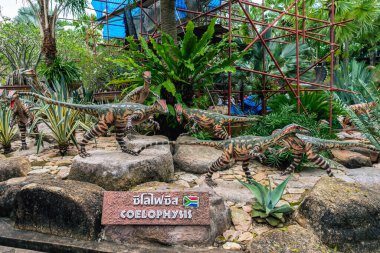 PATTAYA, THAILAND-DECEMBER 30. 2018: Nong Nooch Tropikal Botanik Bahçesi 'ndeki canlı benzeri manzaraya karşı heykeli veya çeşitli gerçekçi dinozor heykeli olan dinozor vadisi.