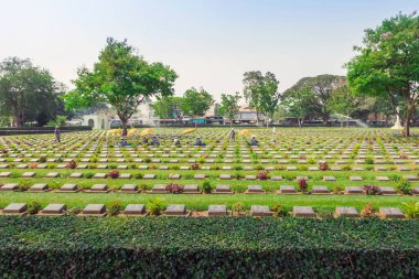 KANCHANABURI THAILAND - 21 Şubat: Kimliği belirsiz işçiler, 21 Şubat 2020 'de Kanchanaburi, Tayland' daki Kanchanaburi Müttefik Savaş Mezarlığı 'nda çiçek yenileyip dekore ediyorlar