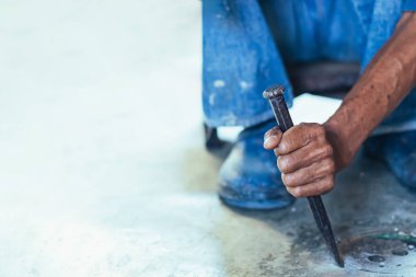 Su hizmetleri bakım servisinin yaşlı çalışanı evdeki kanalizasyon kanallarını değiştiriyor. Yaşlı adamın elleri kanalizasyon sisteminin lağım kapağını değiştirip onarıyor. Tuvalet drenaj sisteminin bakımı.