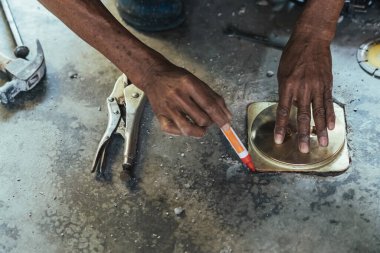 Su hizmetleri bakım servisinin yaşlı çalışanı evdeki kanalizasyon kanallarını değiştiriyor. Yaşlı adamın elleri kanalizasyon sisteminin lağım kapağını değiştirip onarıyor. Tuvalet drenaj sisteminin bakımı.