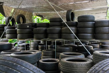 Eski model, araba tamirhanesinde üst üste yığılmış pek çok tekerlek kullanırdı. Eski siyah lastik lastik yığınları. Arka planda pnömatik lastik yığını var. Geri dönüşüm için eski lastik deposu. Araç parçası. Tekerlek lastikleri