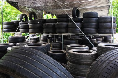 Eski model, araba tamirhanesinde üst üste yığılmış pek çok tekerlek kullanırdı. Eski siyah lastik lastik yığınları. Arka planda pnömatik lastik yığını var. Geri dönüşüm için eski lastik deposu. Araç parçası. Tekerlek lastikleri