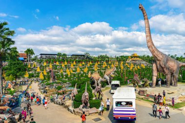PATTAYA, THAILAND-DECEMBER 30. 2018: Nong Nooch Tropikal Botanik Bahçesi 'ndeki canlı benzeri manzaraya karşı heykeli veya çeşitli gerçekçi dinozor heykeli olan dinozor vadisi.