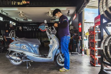 KANCHANABURI, THAILAND - 29 Nisan 2022 Motosiklet tamircisi ve mobilet lambası ampulü ya da motosiklet garajındaki ampulü değiştir. Baştaki lamba prizini değiştir..