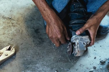 Su tesisatı bakım servisi evdeki kanalizasyon kanallarını değiştirmek için açılı öğütücü kullanıyor. Yaşlı adam kanalizasyon sisteminin lağım kapağını değiştirip onarıyor. Tuvalet drenaj sisteminin bakımı