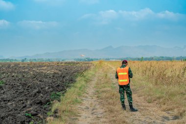 Reconnaissance infantry using cell phones in fields to send news to Combat Headquarters. Army soldier in uniform using mobile phones to inspect surrounding terrain. Military communication technology.