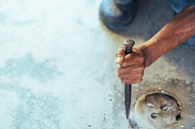 Su hizmetleri bakım servisinin yaşlı çalışanı evdeki kanalizasyon kanallarını değiştiriyor. Yaşlı adamın elleri kanalizasyon sisteminin lağım kapağını değiştirip onarıyor. Tuvalet drenaj sisteminin bakımı.