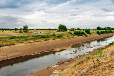 Çatlak beton duvardaki sulama kanalı veya sulama kanalı rezervuardan tarımsal alana su gönderir. River Ovası 'ndaki eski kırık sulama hendeği. Tarım sektöründe çevre felaketi.
