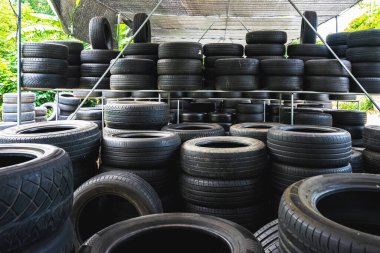 Eski model, araba tamirhanesinde üst üste yığılmış pek çok tekerlek kullanırdı. Eski siyah lastik lastik yığınları. Arka planda pnömatik lastik yığını var. Geri dönüşüm için eski lastik deposu. Araç parçası. Tekerlek lastikleri