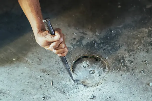 Su hizmetleri bakım servisinin yaşlı çalışanı evdeki kanalizasyon kanallarını değiştiriyor. Yaşlı adamın elleri kanalizasyon sisteminin lağım kapağını değiştirip onarıyor. Tuvalet drenaj sisteminin bakımı.