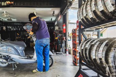 KANCHANABURI, THAILAND - 29 Nisan 2022 Motosiklet tamircisi ve mobilet lambası ampulü ya da motosiklet garajındaki ampulü değiştir. Baştaki lamba prizini değiştir..