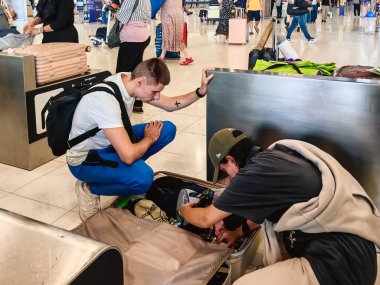 BANGKOK, THAILAND-SEPTEMBER 28, 2024: Tanımlanamayan Turistler, Suvarnabhumi Havaalanı 'ndan uçağa binmeden önce X-ray güvenlik taraması için bavullarındaki eşyaları kontrol edin ve paketleyin..