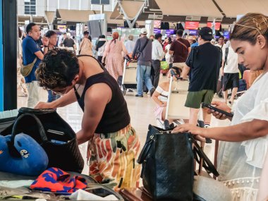 BANGKOK, THAILAND-SEPTEMBER 28, 2024: Tanımlanamayan Turistler, Suvarnabhumi Havaalanı 'ndan uçağa binmeden önce X-ray güvenlik taraması için bavullarındaki eşyaları kontrol edin ve paketleyin..