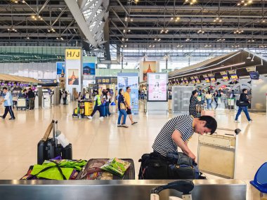 BANGKOK, THAILAND-SEPTEMBER 28, 2024: Tanımlanamayan Turistler, Suvarnabhumi Havaalanı 'ndan uçağa binmeden önce X-ray güvenlik taraması için bavullarındaki eşyaları kontrol edin ve paketleyin..