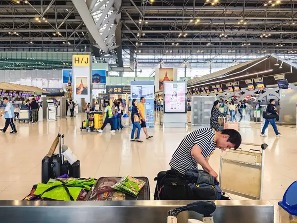 BANGKOK, THAILAND-SEPTEMBER 28, 2024: Tanımlanamayan Turistler, Suvarnabhumi Havaalanı 'ndan uçağa binmeden önce X-ray güvenlik taraması için bavullarındaki eşyaları kontrol edin ve paketleyin..