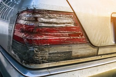 Arabanın stop lambası kırılmış ve şeffaf bantla kapatılmış. Kırık araba durdurma sinyali selobant ile tamir edildi. Hasarlı arabanın arka lambası kazara kırılmış ve şeffaf koli bandıyla kapatılmış.