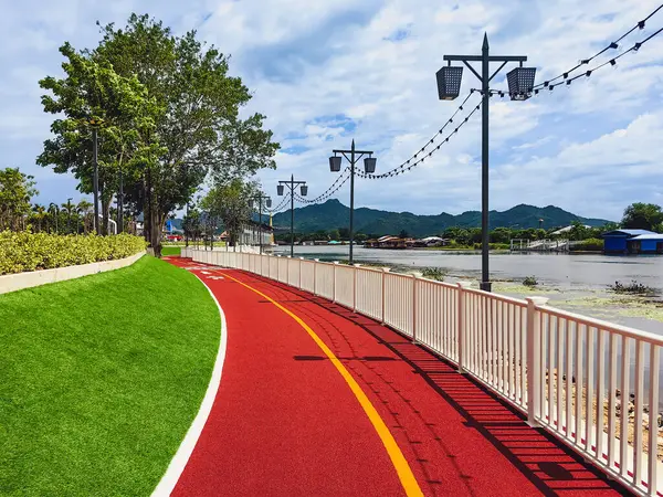 Halka açık güzel yürüyüş yolu manzarası ya da nehir kenarındaki suni çimlerden yapılmış koşu pisti insanların egzersiz yapması, güzel manzaranın tadını çıkarması ve Kanchanaburi, Tayland 'da temiz hava soluması için..