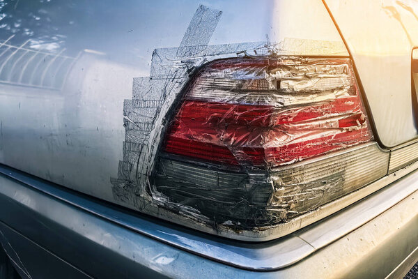 Разбитая задняя фара на машине и запечатана прозрачной лентой. Сломанный сигнал остановки машины отремонтирован скотчем. Хвостовой фонарь поврежденного автомобиля случайно и покрыт прозрачной клейкой лентой, сломан, восстановлен