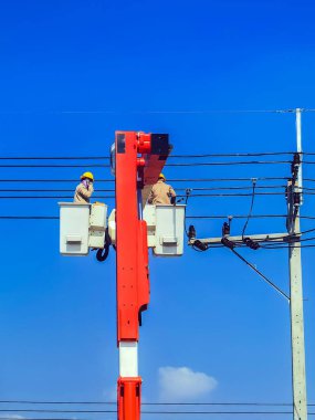Elektrikçiler ya da kova patlatıcısının mühendisi elektrik sistemini elektrik direğine birçok kablo hattıyla yüklemek için çalışıyor. Elektrikçiler elektrik direğindeki kabloyu tamir ediyorlar. Yüksek voltaj güç hattı onarımı