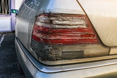 Arabanın stop lambası kırılmış ve şeffaf bantla kapatılmış. Kırık araba durdurma sinyali selobant ile tamir edildi. Hasarlı arabanın arka lambası kazara kırılmış ve şeffaf koli bandıyla kapatılmış.