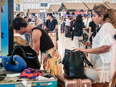BANGKOK, THAILAND-SEPTEMBER 28, 2024: Tanımlanamayan Turistler, Suvarnabhumi Havaalanı 'ndan uçağa binmeden önce X-ray güvenlik taraması için bavullarındaki eşyaları kontrol edin ve paketleyin..