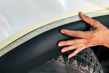 Profesyonel otomobil tamircisi garaja yeni tarz çamurluk fişekleri takıyor. İşçiler direksiyon kemerlerine araba koruması uyguluyorlar. Aracınızın güzelliğini ve güvenliğini arttırın...