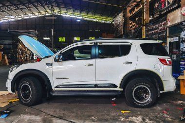 KANCHANABURI, THAILAND-HAZİRAN 5.2022: Tanımlanamayan profesyonel oto tamircisi yeni tarz çamurluk fişekleri takıyor garajdaki SUV aracının tekerlek kemeri. Aracınızın güzelliğini ve güvenliğini arttırın..