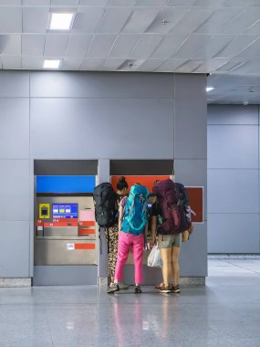 Sırt çantalı beyaz kadın yolculardan oluşan bir grup bilet otomatından bilet alıyor. Kadın turist otomatik otomattan birlikte bilet alıyor. Seyahat ve macera konsepti.