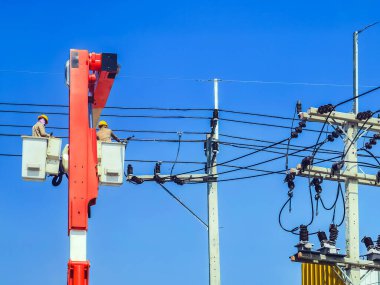 Elektrikçiler ya da kova patlatıcısının mühendisi elektrik sistemini elektrik direğine birçok kablo hattıyla yüklemek için çalışıyor. Elektrikçiler elektrik direğindeki kabloyu tamir ediyorlar. Yüksek voltaj güç hattı onarımı