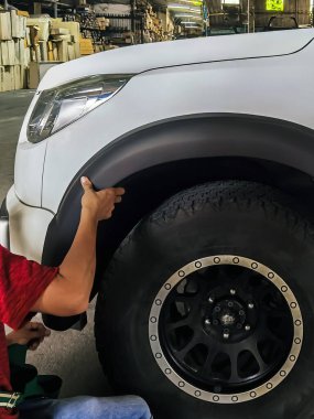Profesyonel otomobil tamircisi garaja yeni tarz çamurluk fişekleri takıyor. İşçiler direksiyon kemerlerine araba koruması uyguluyorlar. Aracınızın güzelliğini ve güvenliğini arttırın...