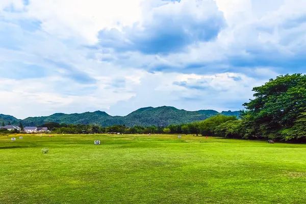 Golf sahası manzarası çimenli yamaçlar, doğal çitleri ve dağı olan uzaklık işaretleri. Mesafe işaretlerini gösteren atış poligonu. Golf ve golf sahasında bahçe işaretleri.