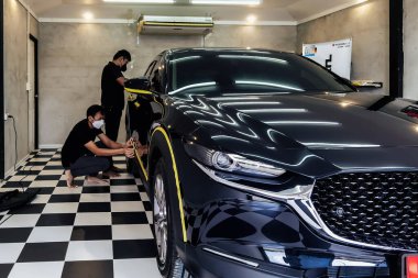 KANCHANABURI, THAILAND-NOVEMBER 12.2021: Tanımlanamayan profesyonel tamirci Mazda CX 30 aracını garajda cilalamak ve koruyucu kaplamalar uygulamak için hazırlayın. Cilalama kavramı için araba gövdesi hazırlığı