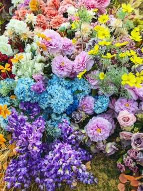 Güzel, canlı, yapay çiçek buketleriyle süslenmiş ve süslenmiş. Arkaplan ya da fon olarak renkli yapay çiçekler. Renkli çiçek desenli duvar kâğıdı. Sevimli çiçekler.