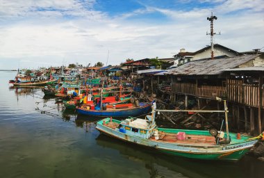 PHETCHABURI-THAILAND, 20 Ağustos 2022: Akşam Phoo Chuk Köprüsü 'nde deniz manzaralı çeşitli renkli balıkçı teknelerinin güzel manzarası. Balıkçı tekneleri balıkçı köyüne yanaştı.