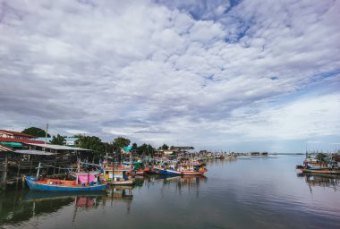 PHETCHABURI-THAILAND, 20 Ağustos 2022: Akşam Phoo Chuk Köprüsü 'nde deniz manzaralı çeşitli renkli balıkçı teknelerinin güzel manzarası. Balıkçı tekneleri balıkçı köyüne yanaştı.