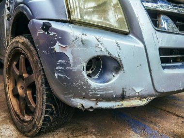 Hasarlı sis lambası lensine yakın ve ön tampondaki boyayı çatlatmış ve soymuş. Araba tamponu derin boya hasarıyla çizilmiş. Dent çizik arabası. Kazara kırık bir araba. Araba çarpması yüzünden kırışıklıklar.