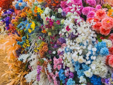 Güzel, canlı, yapay çiçek buketleriyle süslenmiş ve süslenmiş. Arkaplan ya da fon olarak renkli yapay çiçekler. Renkli çiçek desenli duvar kâğıdı. Sevimli çiçekler.