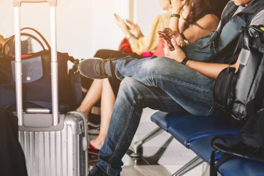 Havaalanı Terminali 'nde uçuş beklerken bavullu cep telefonu kullanan erkek turistlerin elleri. Adamın elleri kalkış kapısında uçağa binmek için beklerken cep telefonu kullanıyor..