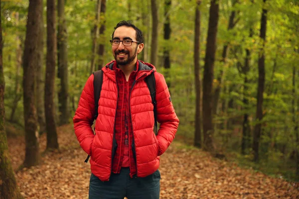 Stock image Trekking lover, adventurer bearded Caucasian man posing in front of a green blurry background in the forest