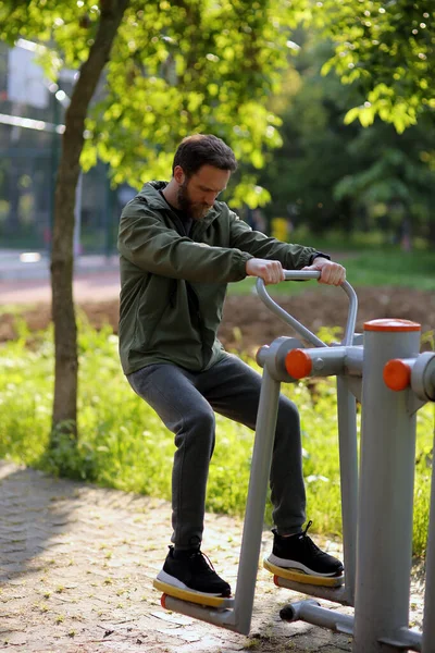 stock image Bearded Caucasian man using public exercise equipments in the park